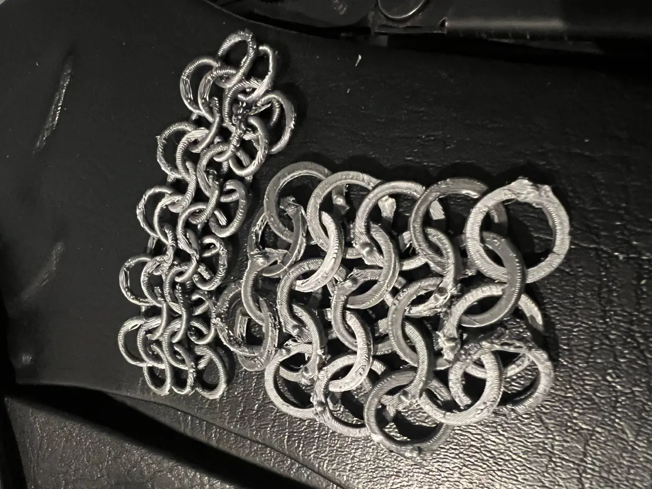 Two small sections of chainmail, one plain rings and the other flattened rings with fake rivet bumps