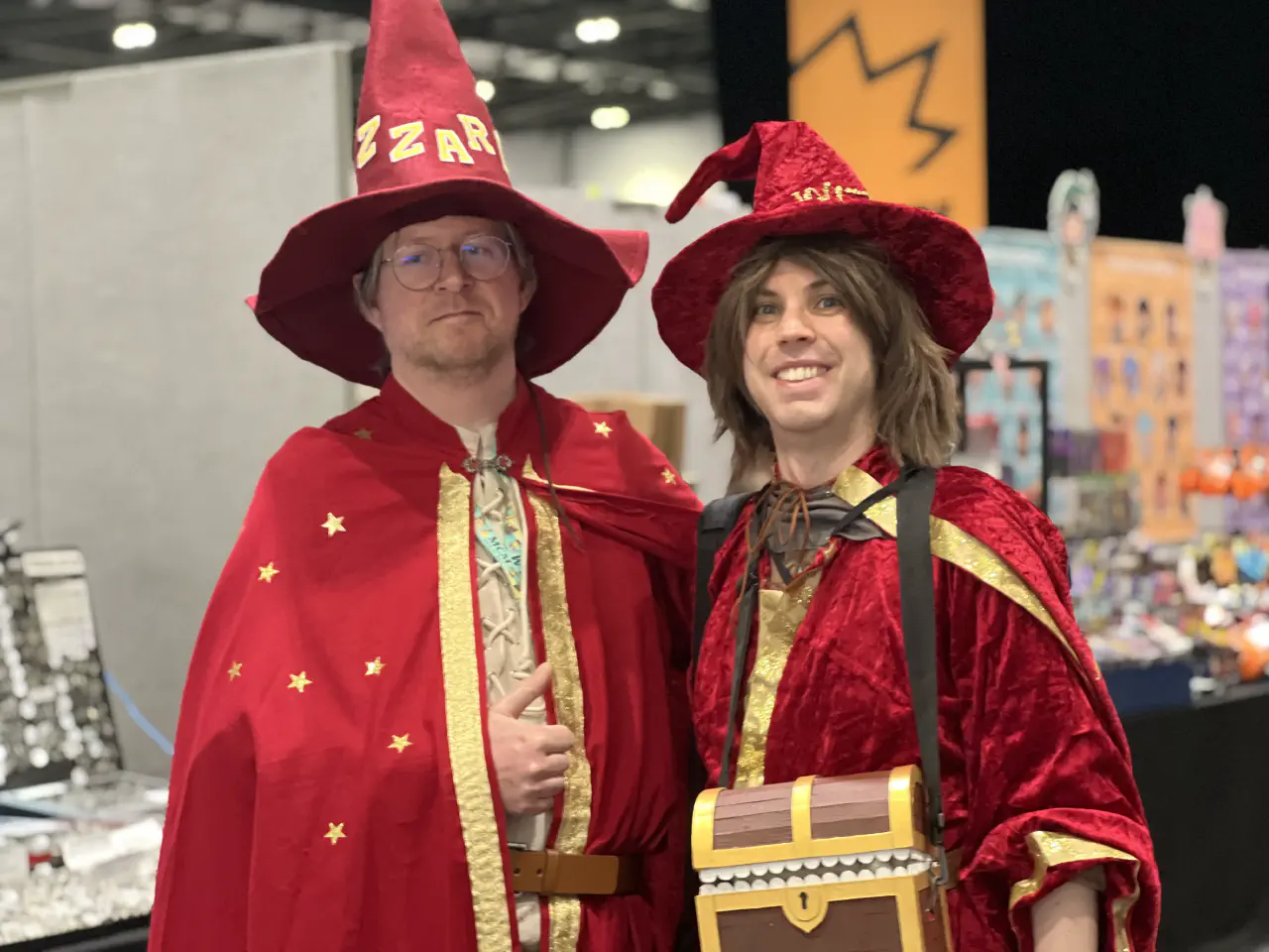 Two people in red robes and pointy hats standing next to each other. They are both dressed as Rincewind.