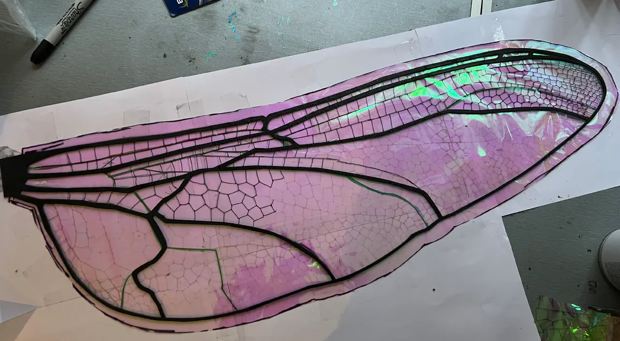 A wing structure with a single layer of film. There are sharpie lines drawn over half to look like a dragonfly wing.