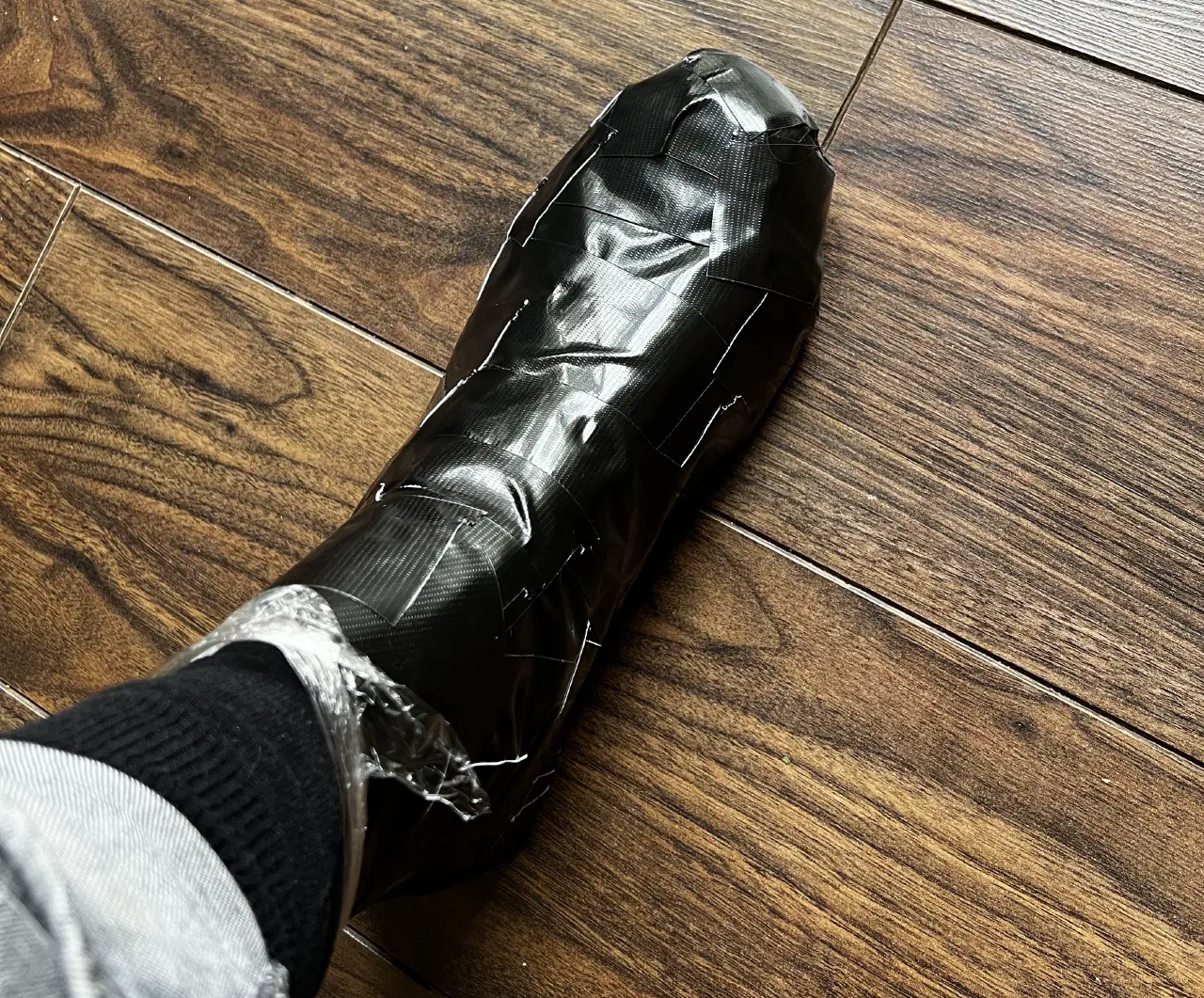 A foot entirely wrapped in black duct tape seen from above.